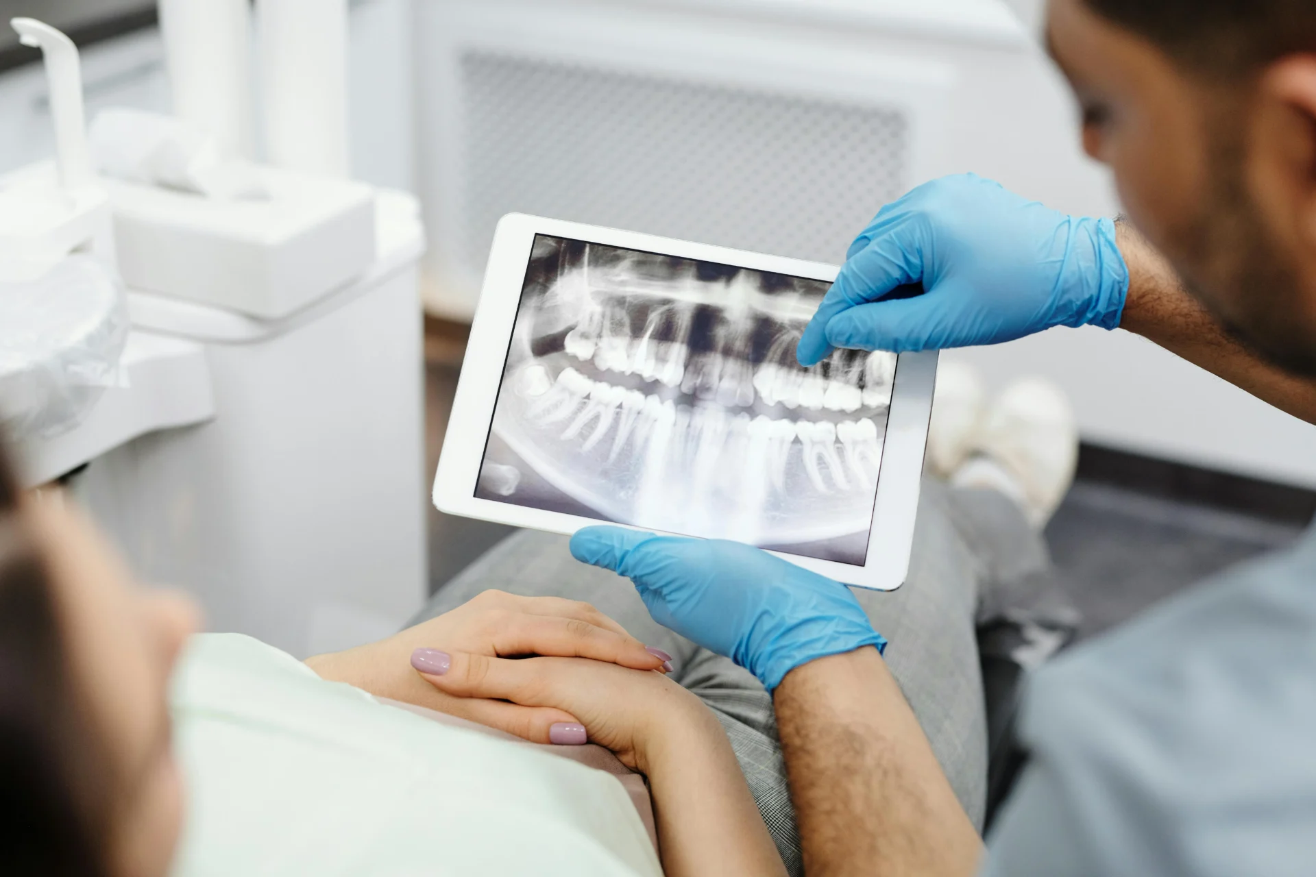 Dentist reviewing a dental X-ray on a tablet during a check-up consultation.