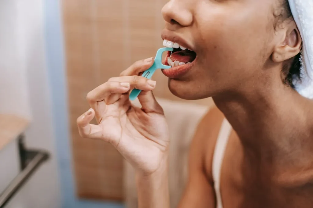 Person using a floss to clean between teeth and reduce bleeding gums.