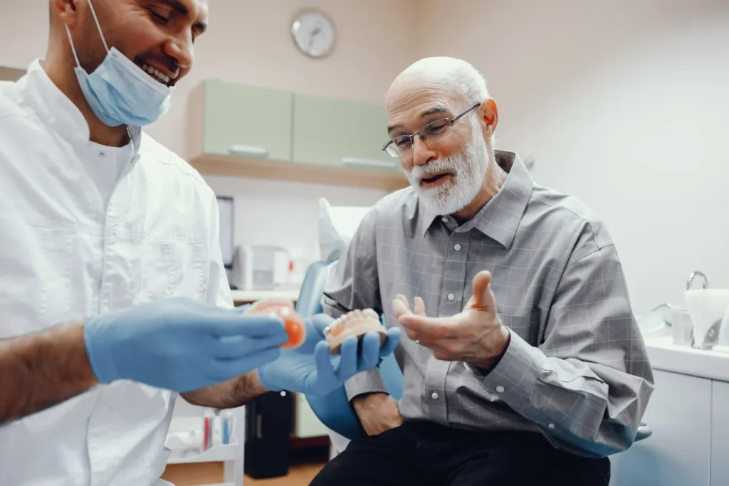 Dentist explaining a dental implant model to a patient during a consultation.