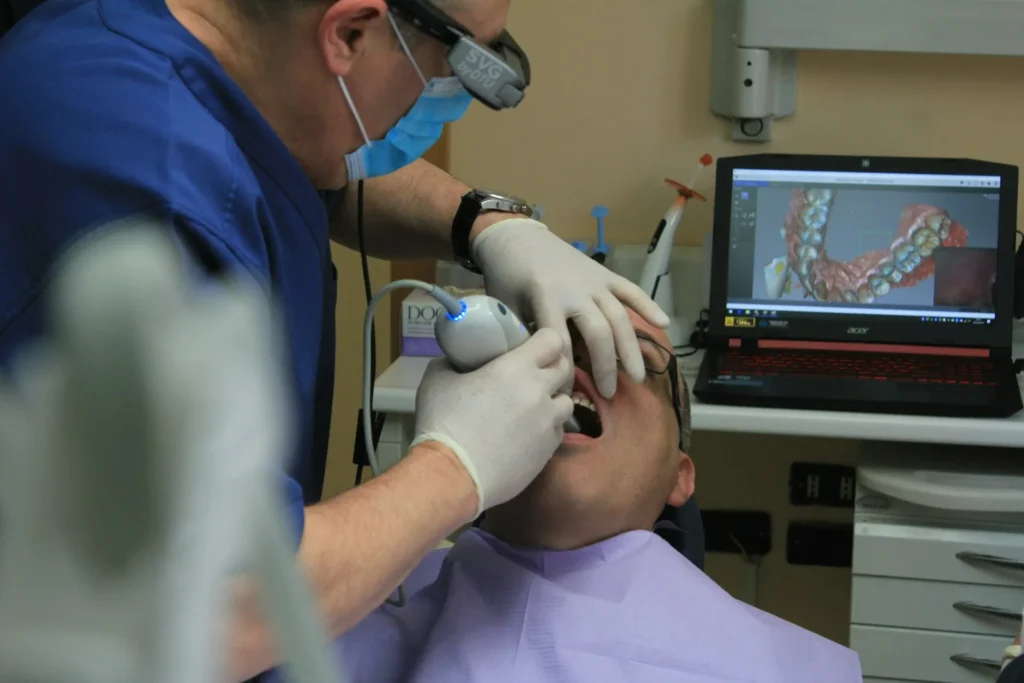 Dentist using a digital scanner to assess teeth alignment and overbite before Invisalign treatment.