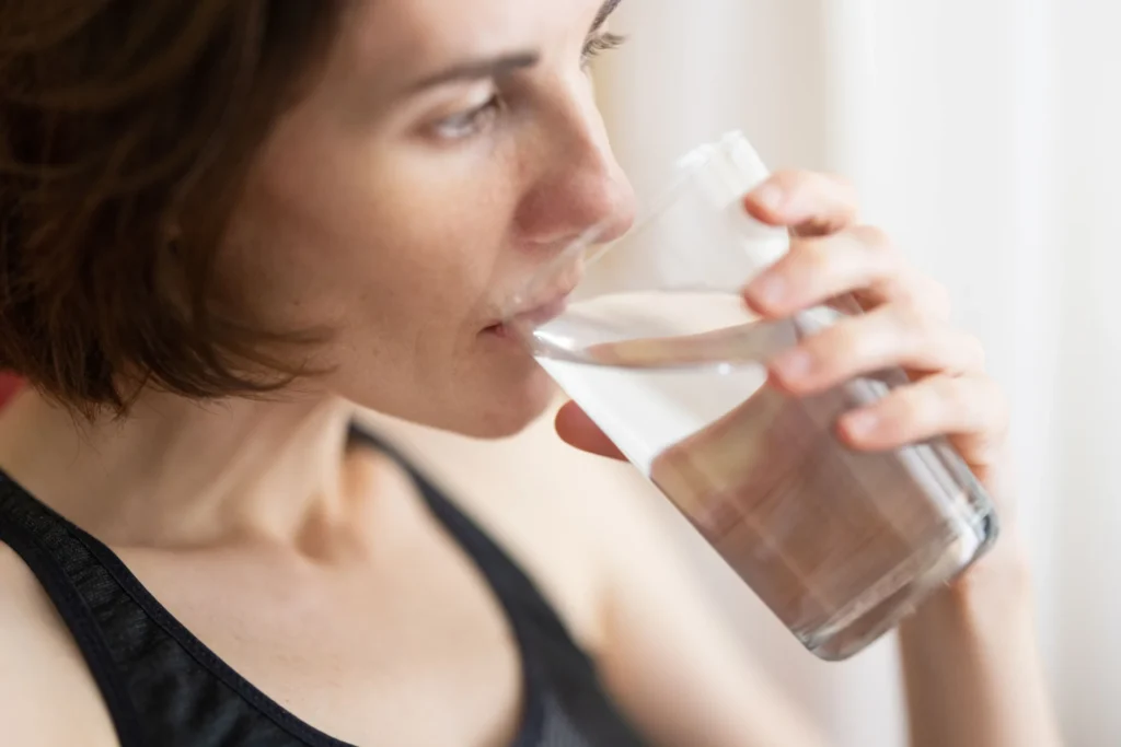 Woman drinking a glass of water while managing sensitive teeth.