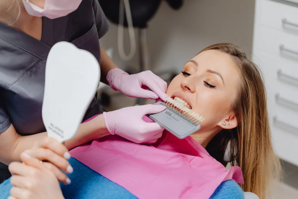 Dental professional comparing a patient's teeth with a tooth shade guide.
